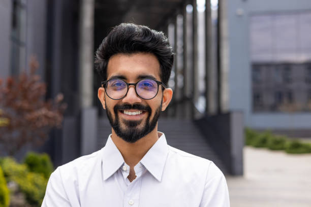 istock Confident young entrepreneur with a beard smiling outdoors, modern office building background 1968122539