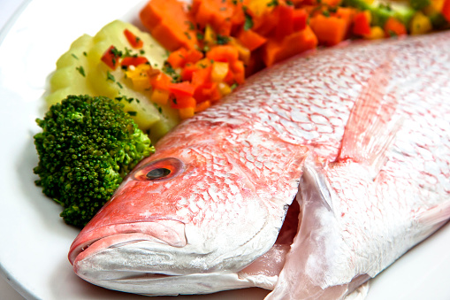 Fresh red snapper or red snapper ready to be cooked with steamed vegetables, close up view