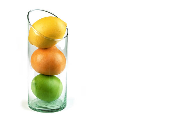 Lemons and oranges together in a glass bowl on white background with space for text