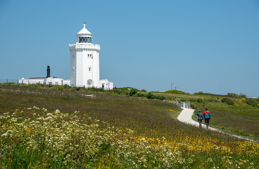 People walking on the coastline route footpath. South foreland light houses. White cliffs of Dover Kent.