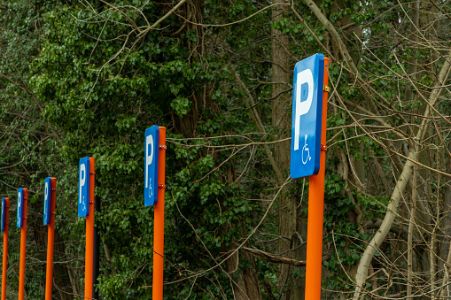 Multiple parking spaces reserved for disabled in park. Blue parking signs for invalid. Places for disabled cars.
