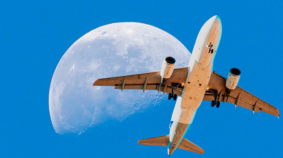 A commercial airliner soars gracefully across a moonlit sky