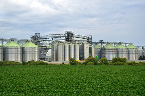 Industrial buildings and manufacturing equipment near an agricultural field. Elevator