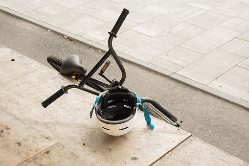 A trick bicycle stands on the ramp with a helmet hanging on the handlebars