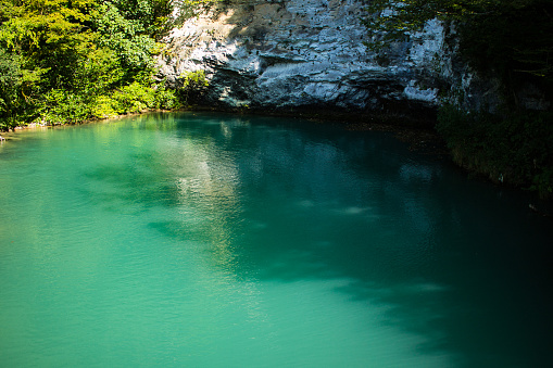 A blue lake among rocky hills and trees in Abkhazia on a sunny summer day