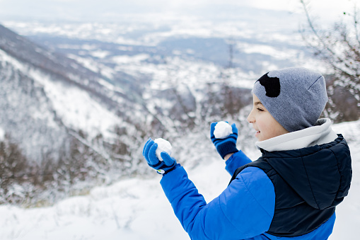 Portrait of a boy in warm winter clothing on the mountain peak.