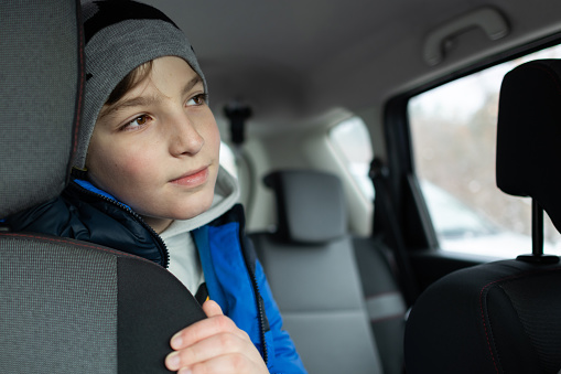 Portrait of a boy in a car in warm winter clothing.