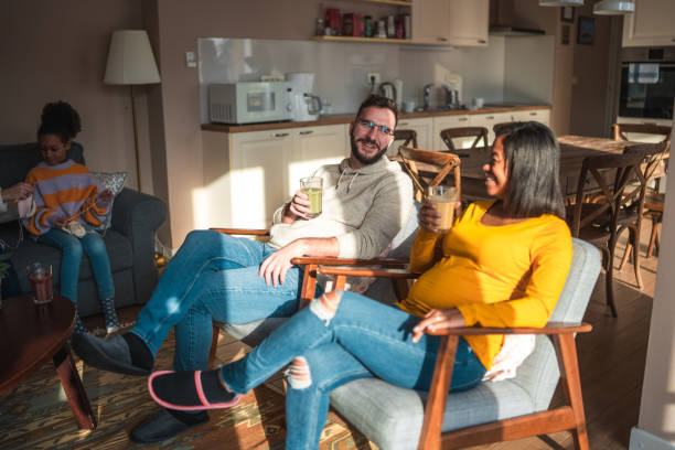 istock Diverse Couple Relaxing Indoor With Drinks, Child in Background 1968244534