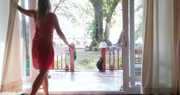 istock Mature woman opens curtains in morning 1968246124