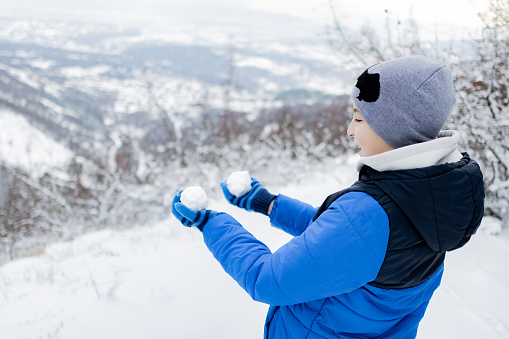 Portrait of a boy in warm winter clothing on the mountain peak.