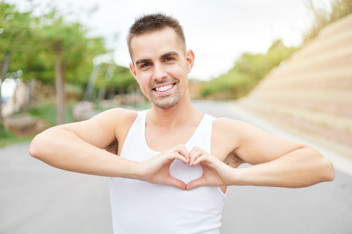 Young gay man making heart shapes with his hands. Concept of peace, love and gender equality.