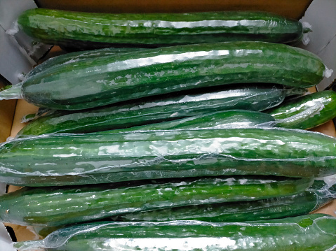 Laminated Dutch cucumbers in a cardboard box in close-up detail.