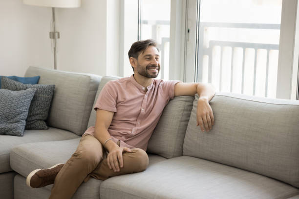 istock Positive thoughtful relaxed middle aged man sitting on comfortable couch 1968410404