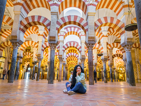 tourist woman seated on the floor of the Mezquita (Spanish for mosque) of Cordoba is a Roman Catholic cathedral and former mosque situated in the Andalusian city of Codoba, Spain