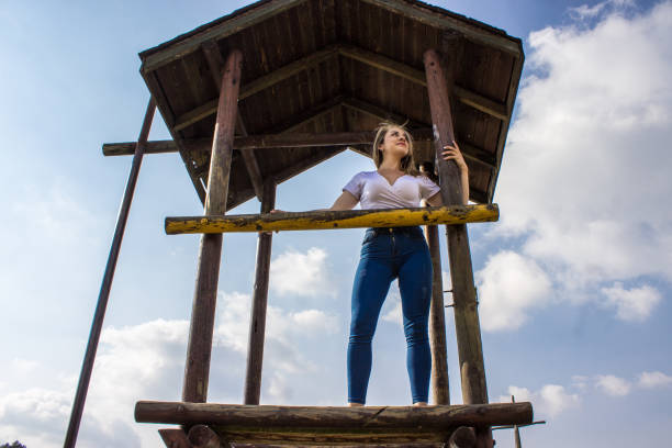 A teen girl smiles at the camera as she sits on the front porch of an old rustic cabin.