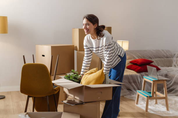istock Smiling positive young woman surrounded by boxes while moving, unpacking personal belongings 1968467514