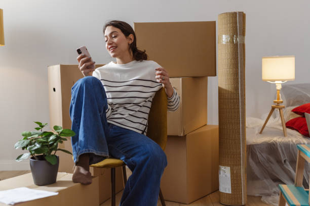 istock Young woman using smart phone in her new apartment 1968478374