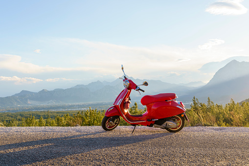 Red moped scooter parked by the mountain road at sunset, Antalya, Turkiye