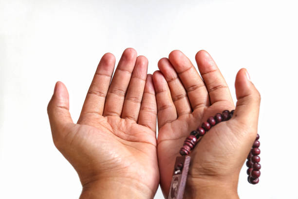 Muslim praying holding prayer beads, close up, isolated on white