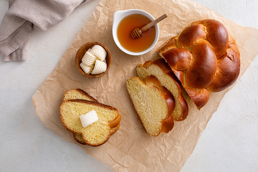Freshly baked hallah sliced served with butter and honey, overhead shot