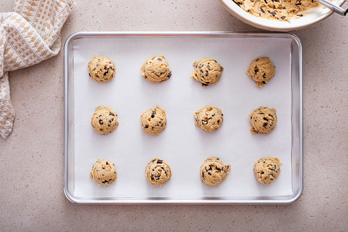 Chocolate chip cookie dough scooped on a cookie sheet ready to be baked