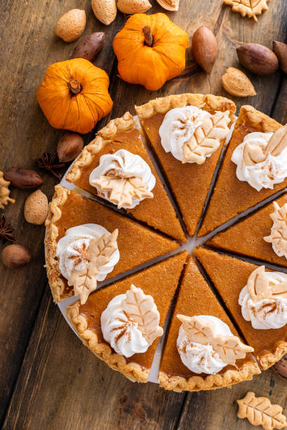 Traditional pumpkin pie topped with whipped cream cut into slices