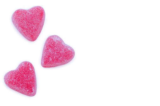 Side border of pink hearts of sugared marmalade on a white background greeting card for Valentine's day.