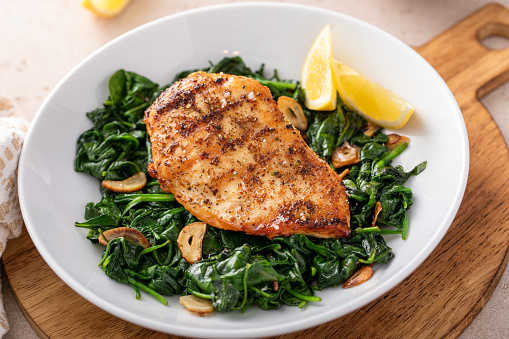 Grilled chicken breast with sauteed garlic spinach and lemon, healthy lunch idea