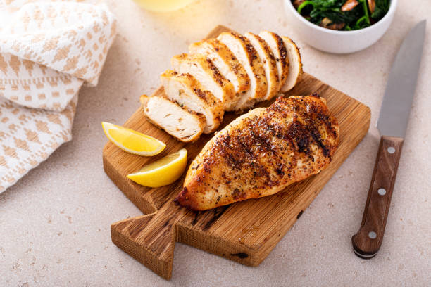 istock Grilled chicken breast, whole and sliced on a cooking board 1968568424