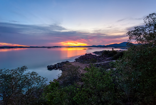 Sun is setting over by the sea, horizon.