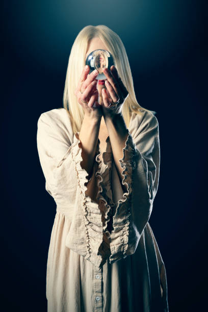 A woman's upside down face reflecting though the crystal ball that she is holding.