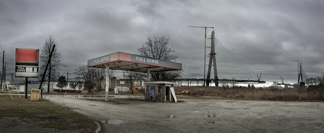 The Gordie Howe International Bridge, is expected to be fully constructed and open for business by 2024/2025.   The bridge will link Detroit, Michigan with Windsor, Ontario.  In the foreground, an abandoned gas station can be seen.