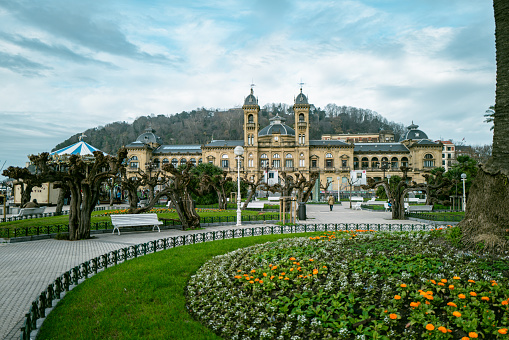 1st January 2024, San Sebastián，Basque Country, Spain: Locals and Tourists walking past city hall. San Sebastián is famous for its longest beach in Europe and incredible food culture. The cityscape can be seen in the background.