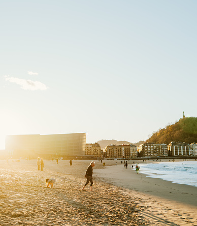 1st January 2024, San Sebastián, Basque Country, Spain: Locals and Tourists enjoying the sunset at La Concha beach on a sunny day. San Sebastián is famous for its longest beach in Europe and incredible food culture. The cityscape can be seen in the background.