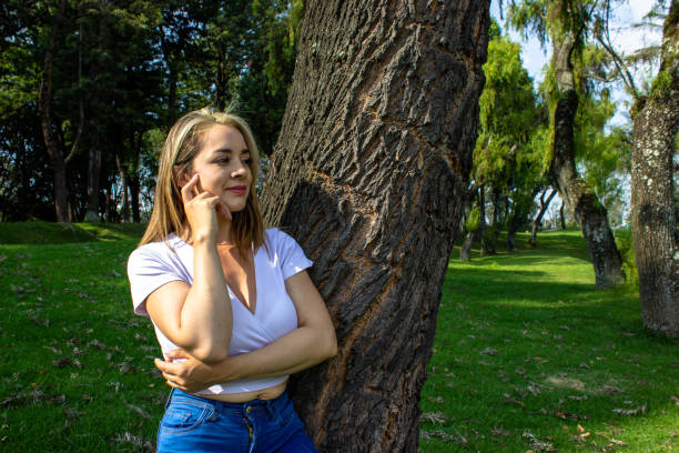 Beautiful young woman posing next to a tree
