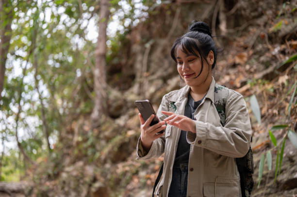 istock A positive Asian woman with a backpack is using her smartphone while hiking on the mountain. 1968849185