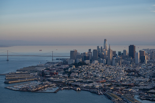 Aerial view across bay to city skyline and bridge at sunset, San Francisco