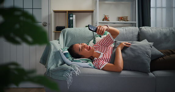 Selective focus, Relaxed young woman holding smart phone looking at screen laughing on the couch at home.enjoying leisure time with telephone,having fun