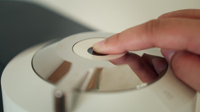 Hand pressing a button on a coffee maker