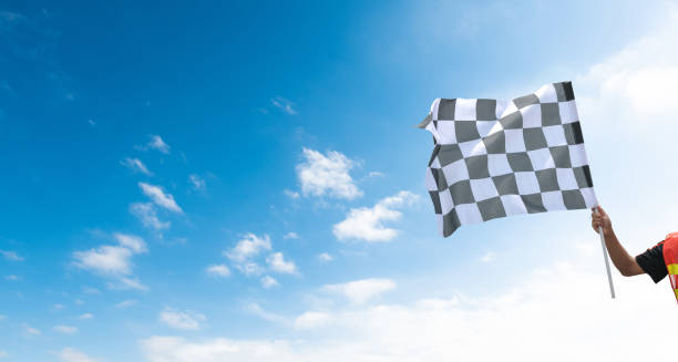 istock Checkered race flag in hand against blue sky 1968964978