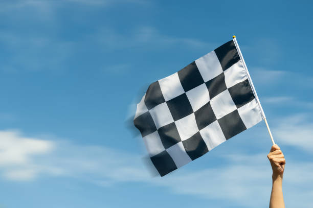 Checkered race flag in hand against blue sky
