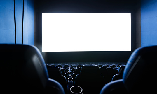 Dark movie theatre interior with screen and chairs