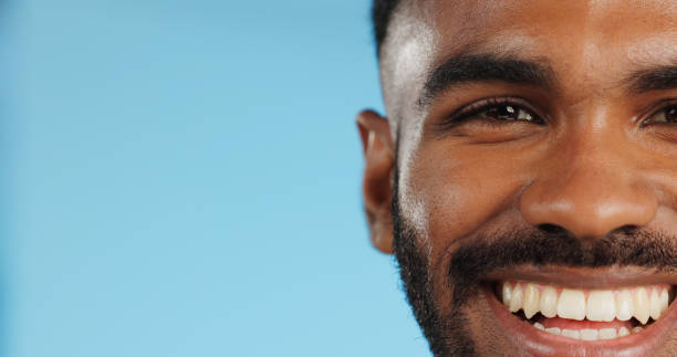 istock Half, face and black man with smile in studio, blue background and mockup space with happiness or advertising. Portrait, closeup and marketing for skincare, wellness or healthy dermatology care 1969010025
