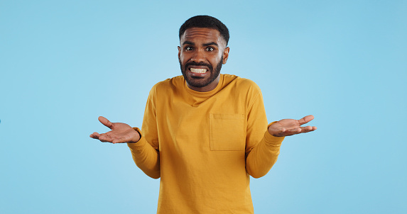 Confused, hands and face of man in studio with don't know, gesture or ask on blue background. Why, portrait and guy model with oops, mistake or doubt, unsure or forget, guess or palm scale questions