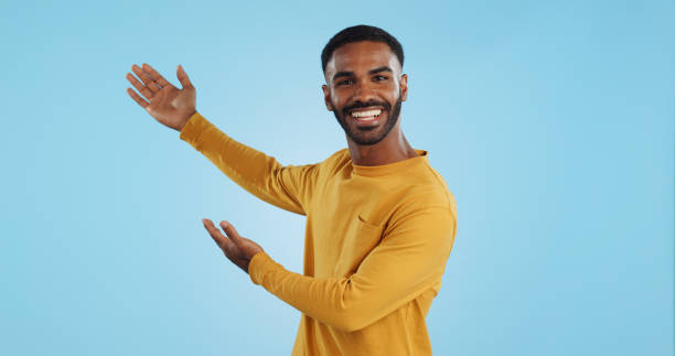 istock Happy, face and man with hand pointing in studio for news, presentation or platform offer on blue background. Smile, portrait and male model show promo, launch or space for coming soon announcement 1969010561