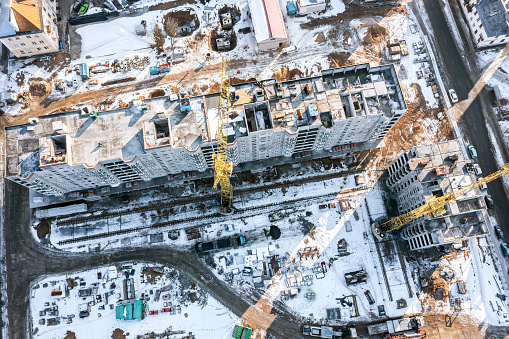 snow-covered construction site with new apartment building under construction. drone photo.
