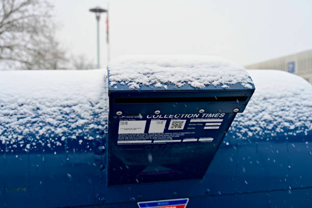 Merrifield, Virginia, USA - January 15, 2024: Freshly fallen snow covers the top of a large mail deposit box at the U.S. Postal Service’s Merrifield processing center during the first significant winter storm of the year in the Northern Virginia area.