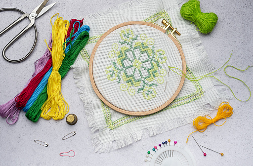 Embroidery with colored threads and various sewing accessories on the table