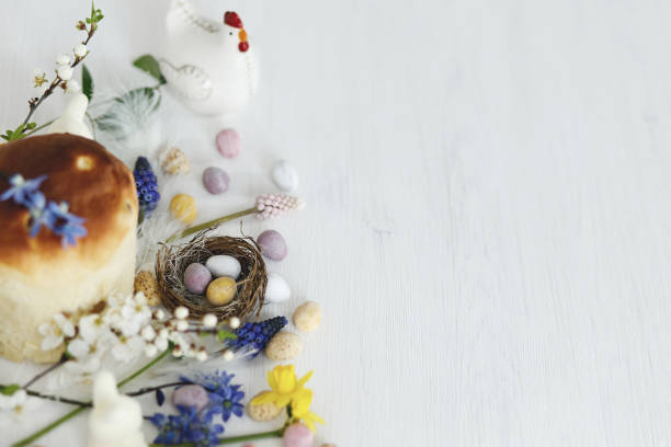 istock Colorful easter chocolate eggs in nest, spring flowers, traditional bread composition on rustic white wooden table. Space for text. Happy Easter! Seasons greetings 1969172828
