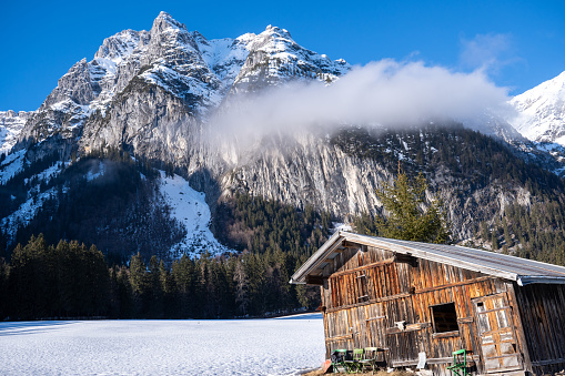 Scenic winter landscape on the top of the mountain, white snow, a rooftop of wooden hut, alps